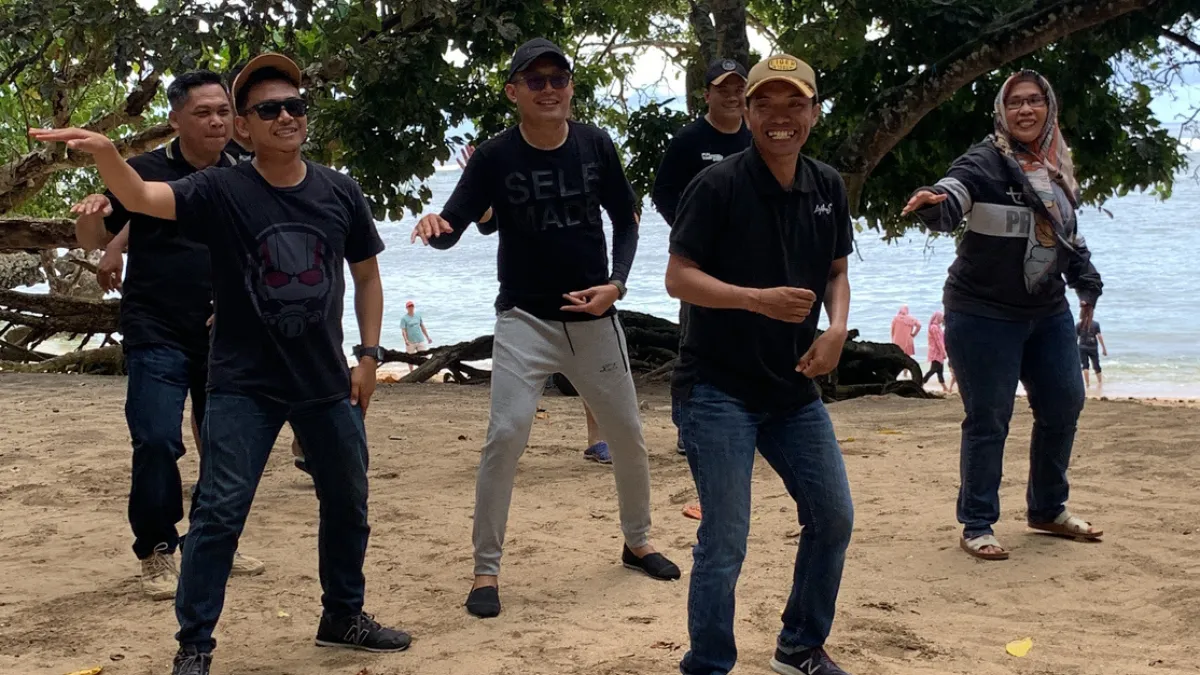 Karyawan bermain games pantai bersama saat outbound